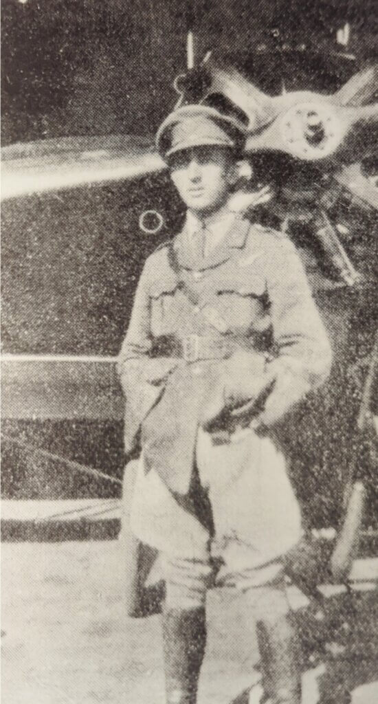 a black and white photo of a man standing in front of a plane